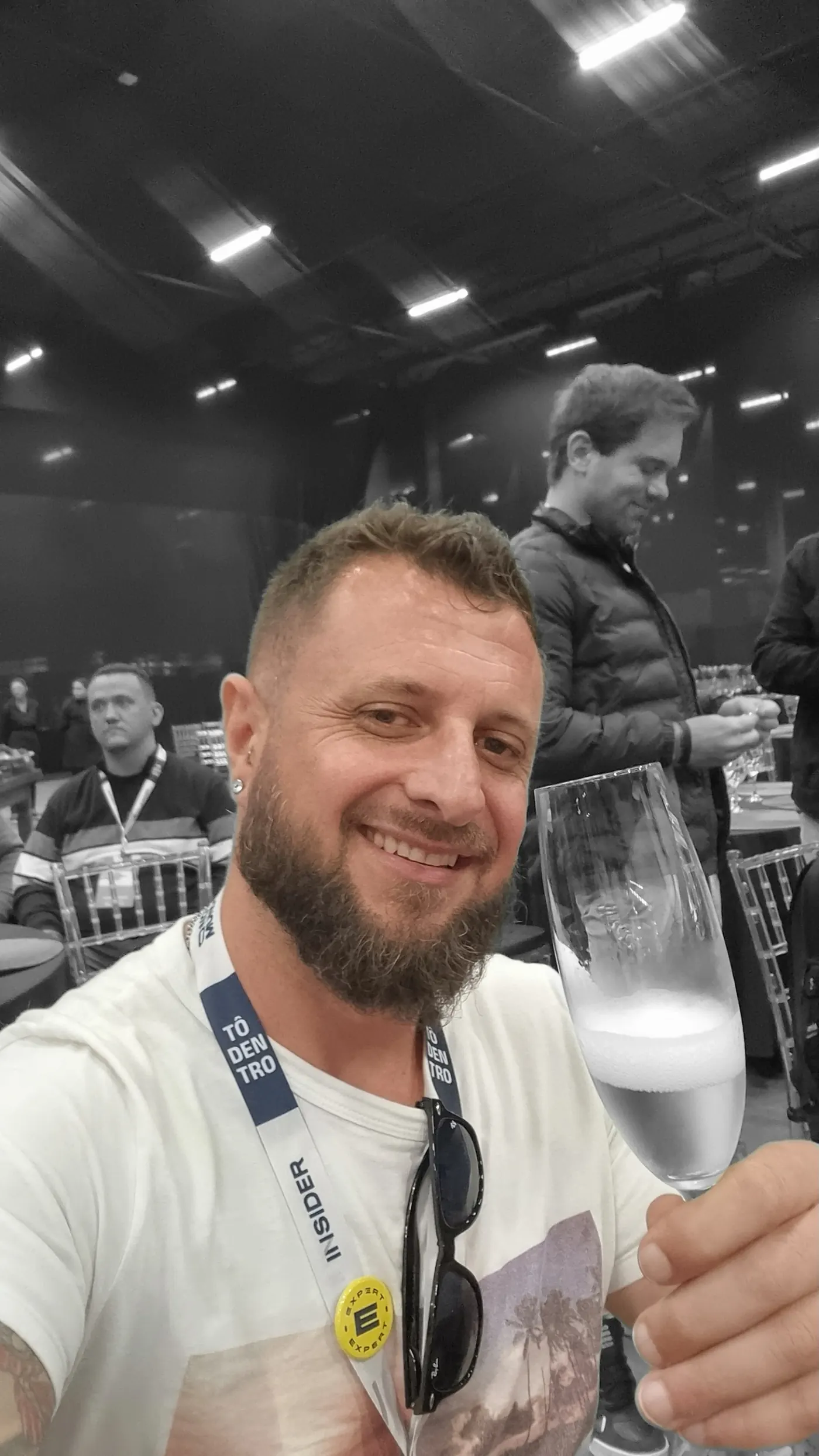 André Luís erguendo um copo, de crachá, num evento de formação